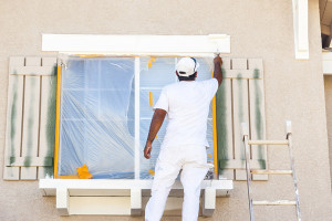 Back view of painter painting a wall with paint roller, with copy space